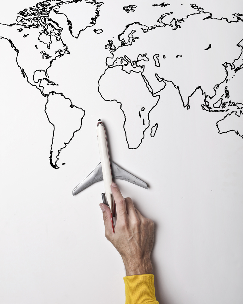 Person holding small toy airplane against black and white map as concept of travel and vacation